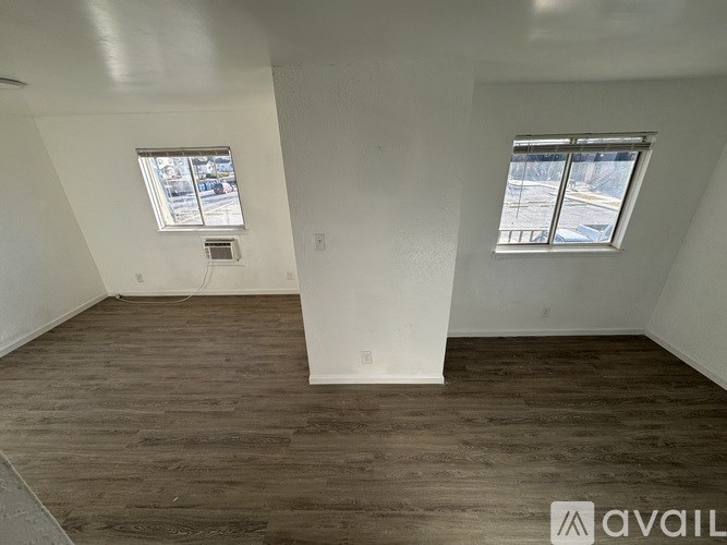 A room with wooden floors and two windows.