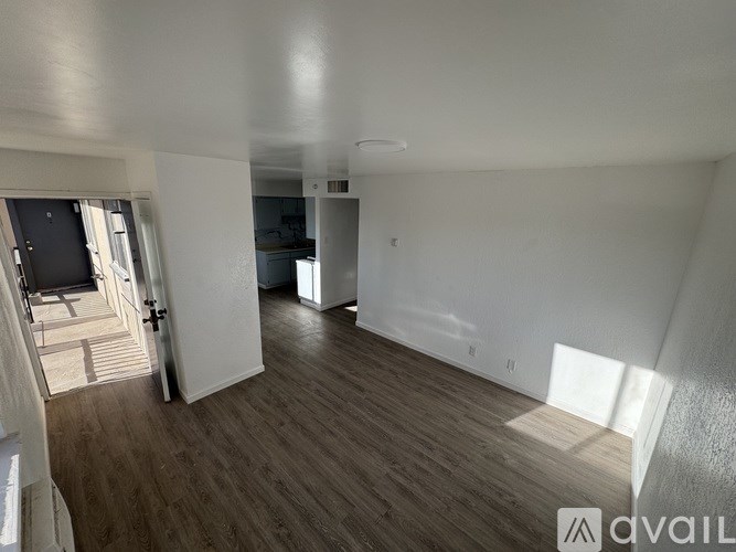 A spacious room with wooden flooring and white walls.