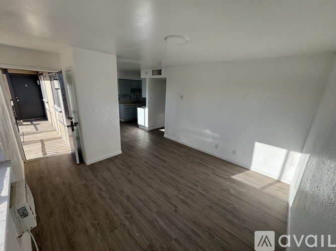 A spacious room with wooden flooring and white walls.