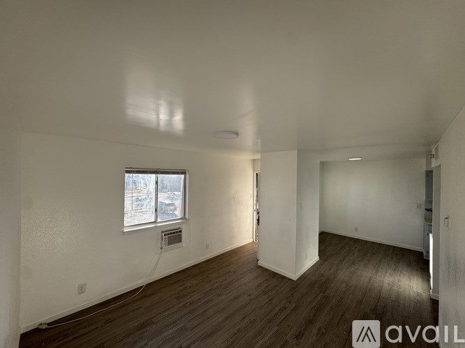 A spacious room with wooden floors and a window with a view of a snowy landscape.