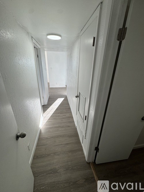 A long hallway with white walls and doors on both sides.
