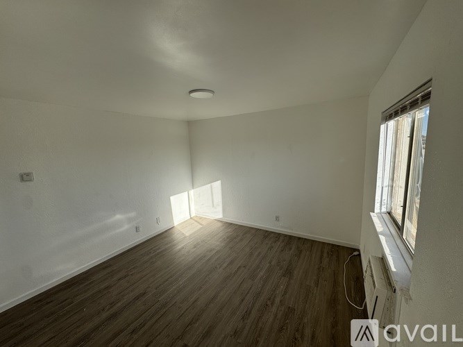 A room with wooden floors and a window letting in sunlight.