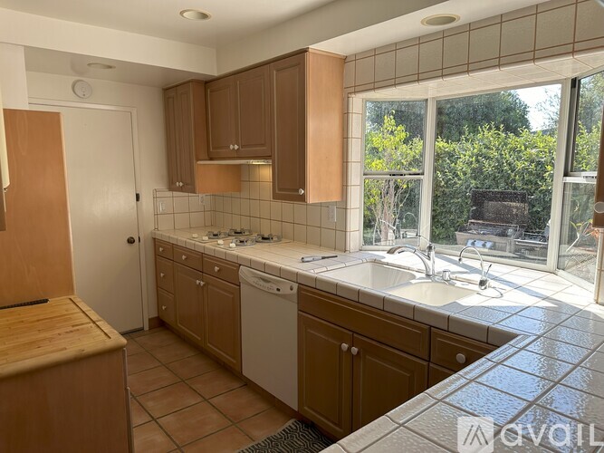 A kitchen with brown cabinets and a white dishwasher.