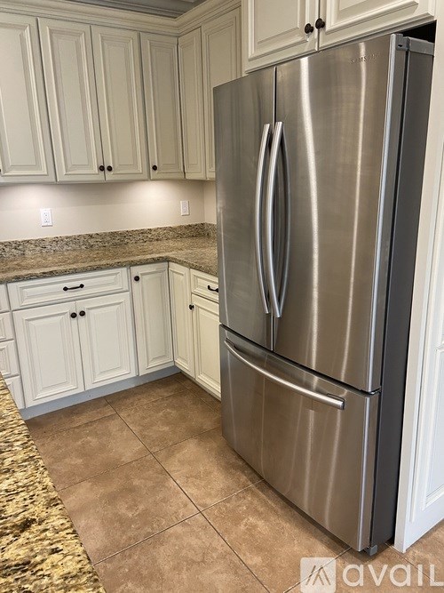 A stainless steel refrigerator in a kitchen with white cabinets.