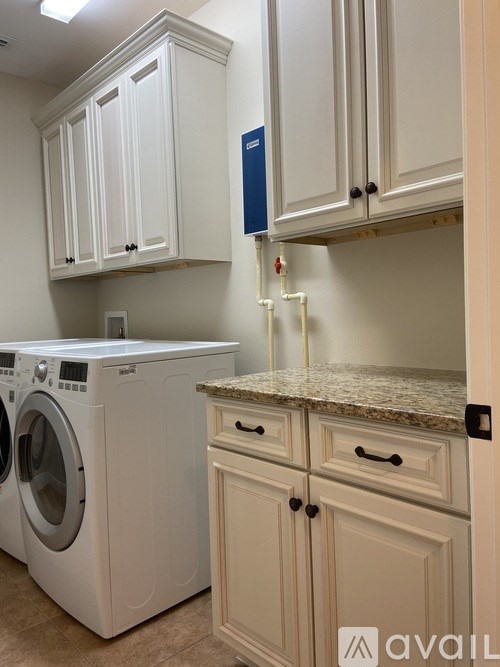 A laundry room with a washer and dryer, cabinets, and a countertop.