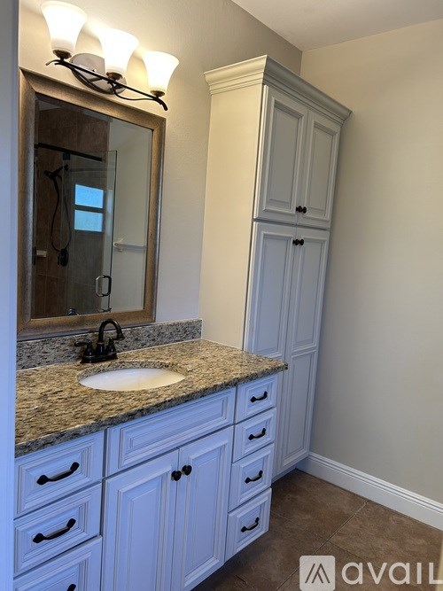 A bathroom with a sink, mirror, and cabinets.