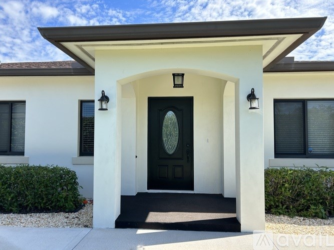 A white house with a black door and two windows.