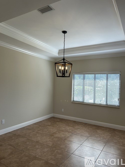 A room with a light hanging from the ceiling and a window with blinds.