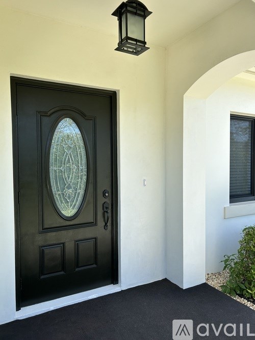 A black door with a glass window in the middle and a black lantern above it.