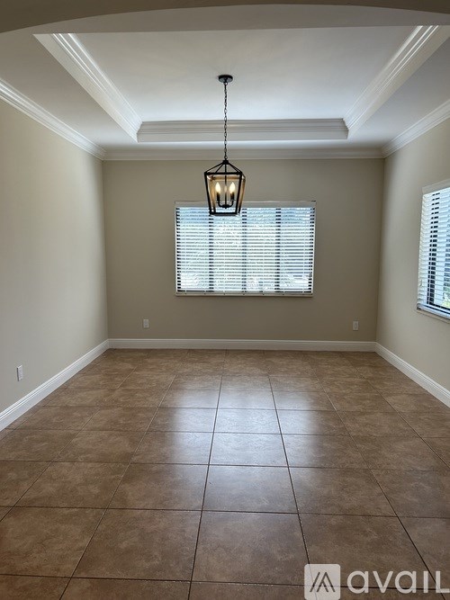 A room with a light hanging from the ceiling and a window with blinds.