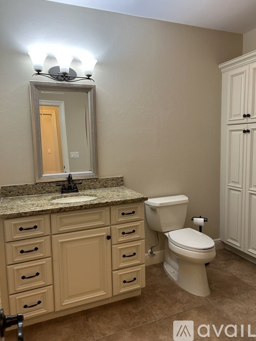 A bathroom with a toilet, sink, and mirror.