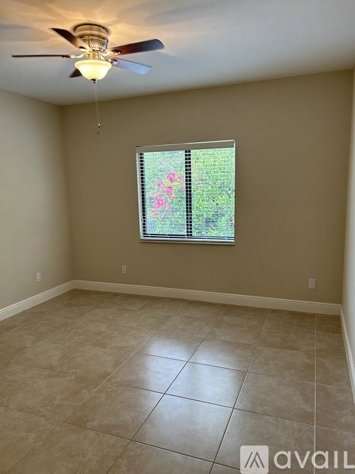 A room with a ceiling fan and a window with a view of trees.