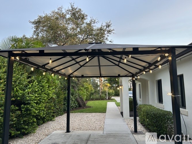 A covered walkway with lights leading to a white building.