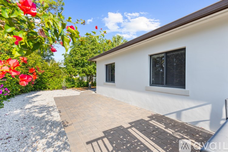 A white house with a brown roof and a brick pathway leading to the front door.
