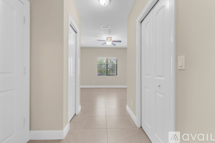A hallway with a fan and a window with blinds.