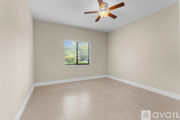 A room with a ceiling fan and a window with blinds.