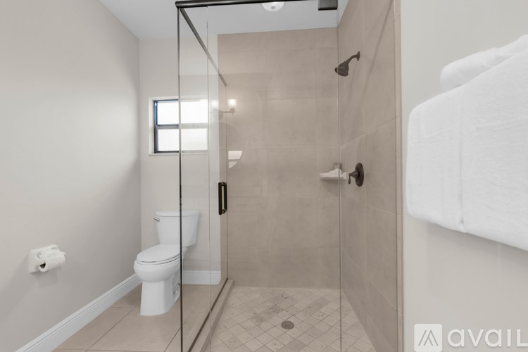 A bathroom with a toilet, a walk-in shower, and a window.