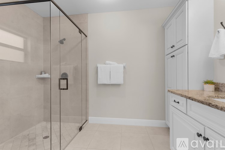 A bathroom with a glass shower stall and a marble countertop.