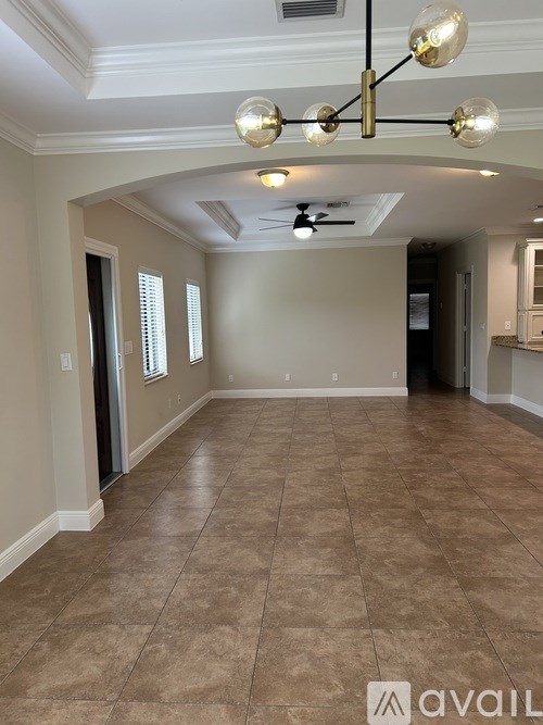 A spacious room with tiled flooring and a chandelier.