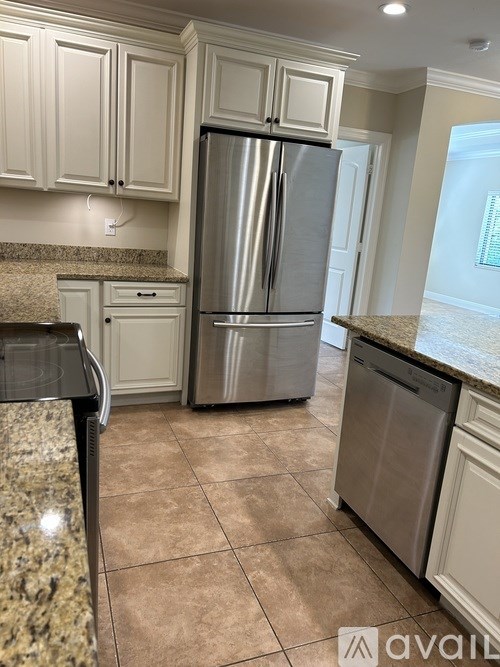 A kitchen with a granite counter top and a stainless steel refrigerator.