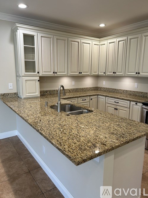 A kitchen with granite countertops and white cabinets.