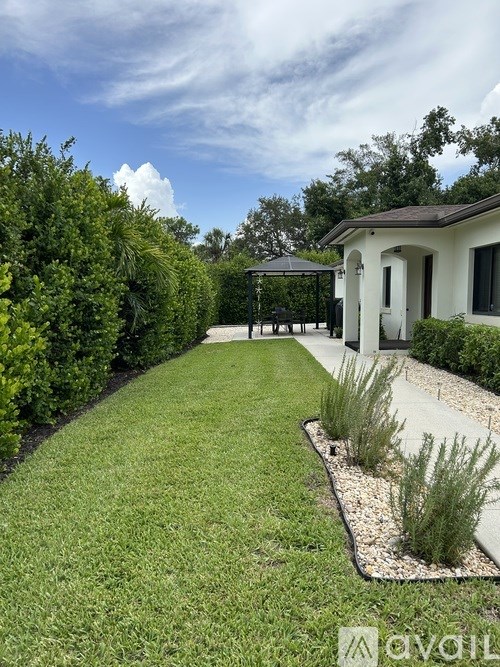 A white house with a garden in front of it.