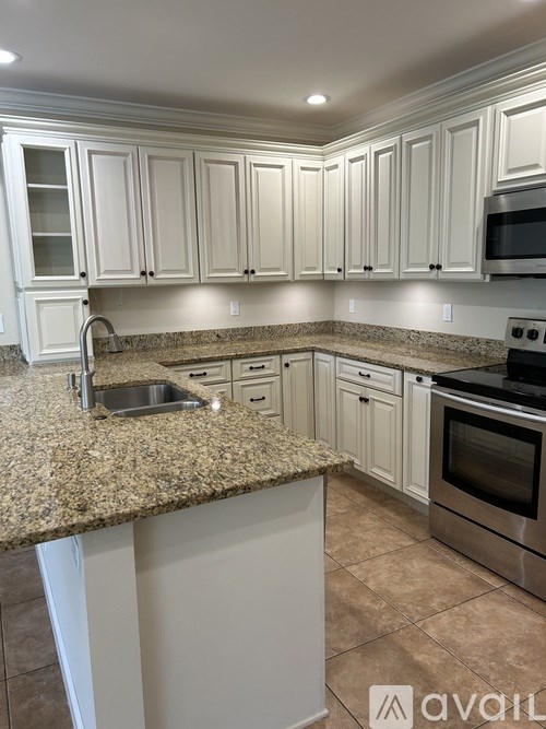 A kitchen with granite countertops and white cabinets.