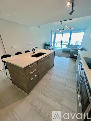 A modern kitchen with a large island and a dining area with chairs.