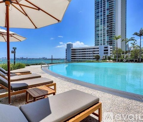 A pool area with lounge chairs and umbrellas overlooking a city skyline.