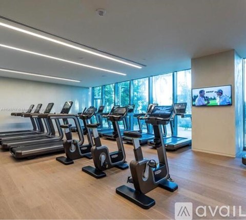 A gym with treadmills and a television screen.