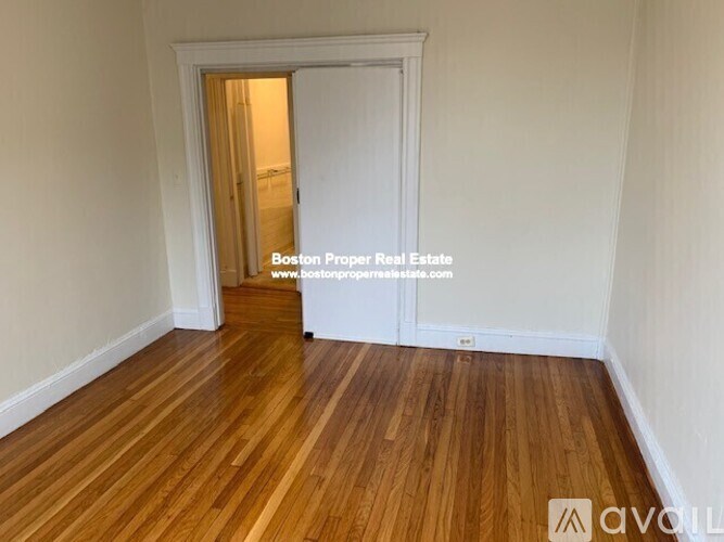 A room with wooden flooring and a doorway leading to another room.