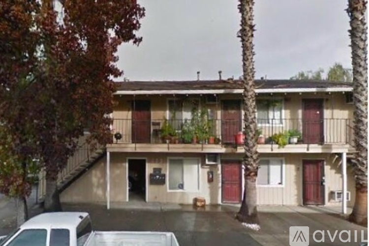 A building with a balcony and a tree in front of it.