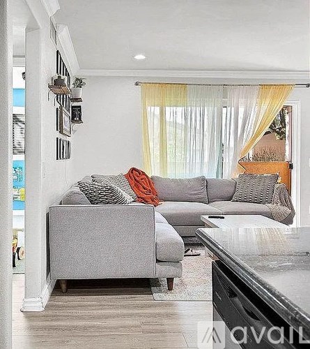 A living room with a grey couch and a black piano.