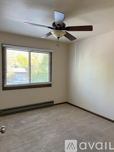 A room with a ceiling fan and a window with blinds.