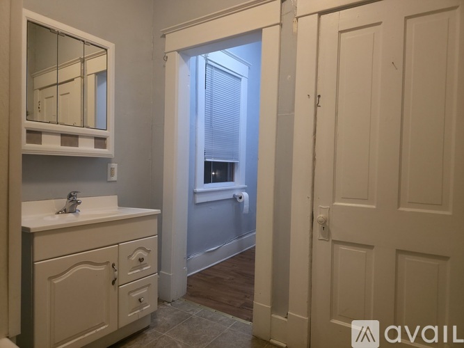 A bathroom with a sink, mirror, and a door leading to a hallway.