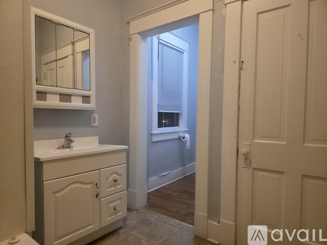 A bathroom with a sink, mirror, and a door leading to a bedroom.