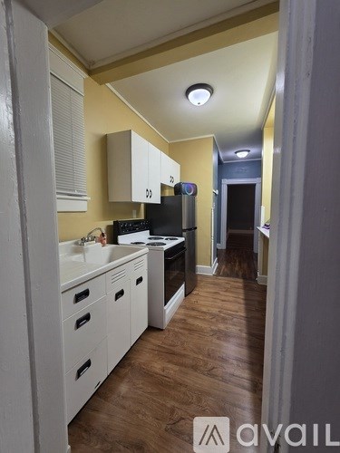 A kitchen with white cabinets and a wooden floor.