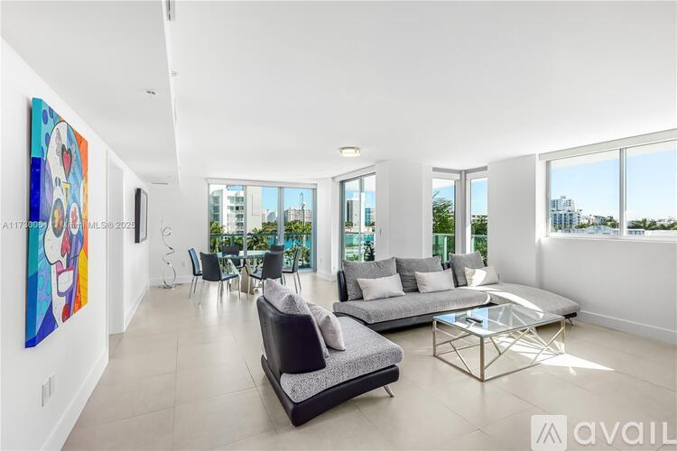 A modern living room with a large painting on the wall and a view of the city outside the windows.