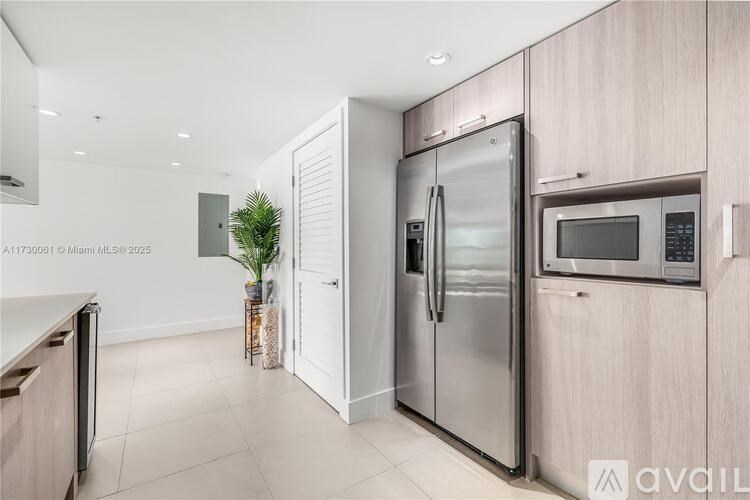 A modern kitchen with a stainless steel refrigerator and microwave.