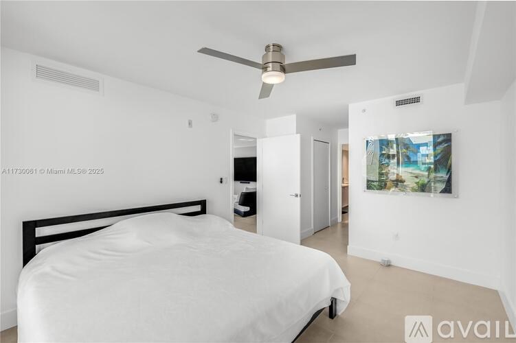 A bedroom with a bed, a ceiling fan, and a painting on the wall.