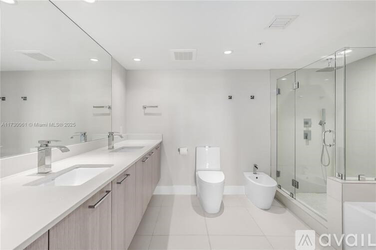 A modern bathroom with a glass shower stall and double sinks.