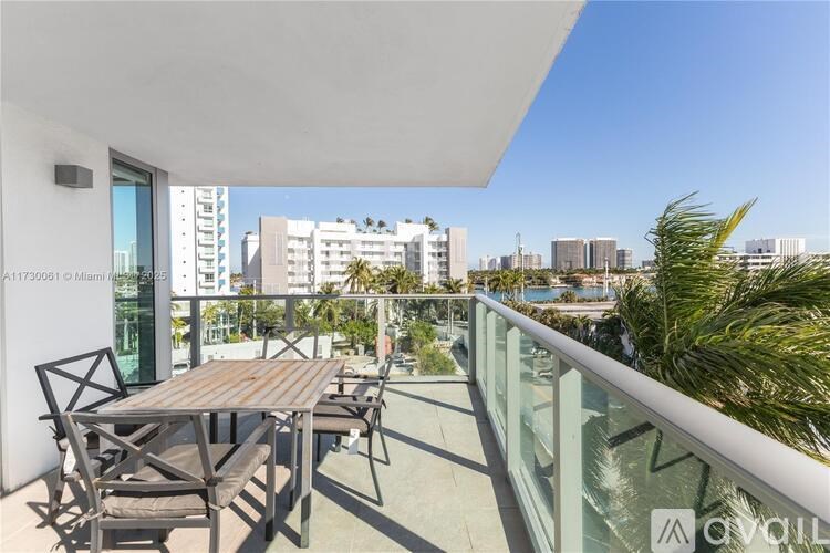 A balcony with a table and chairs overlooks a cityscape.