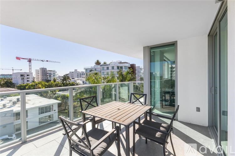 A balcony with a table and chairs overlooking a cityscape.