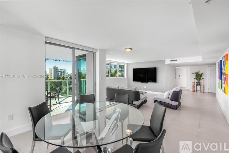 A modern living room with a glass table and black chairs.