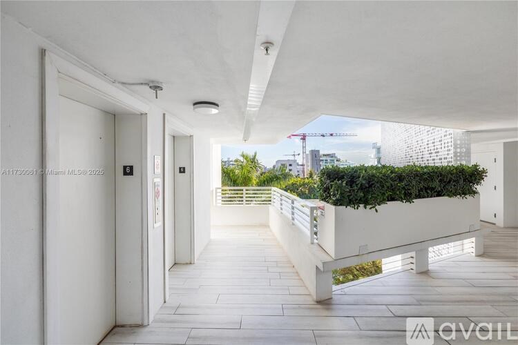 A long hallway with white walls and a green plant on the side.