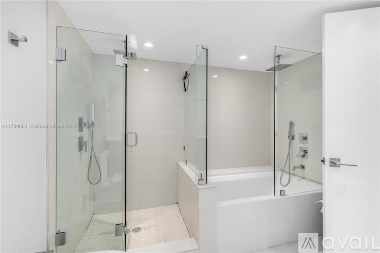 A modern bathroom with a glass shower enclosure and a white bathtub.