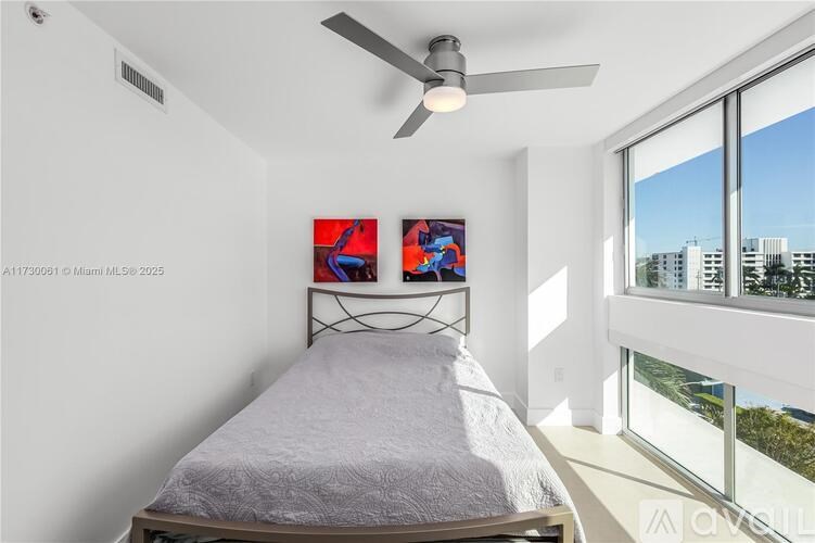 A bedroom with a bed, a ceiling fan, and two paintings on the wall.