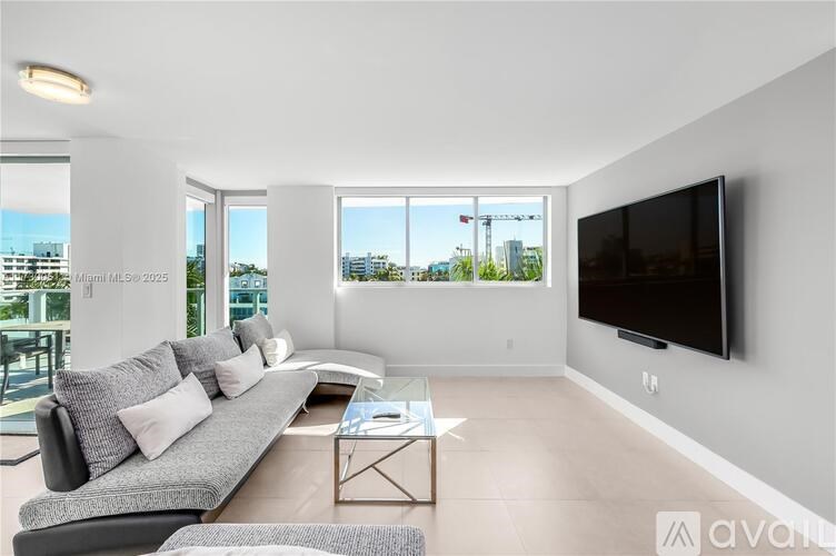 A modern living room with a grey sofa and a flat screen TV mounted on the wall.