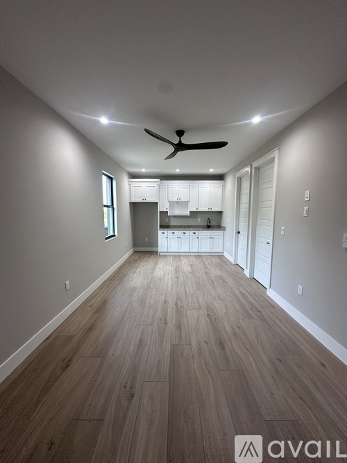 A spacious room with wooden flooring and a ceiling fan.