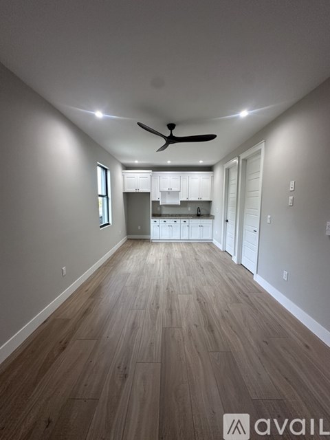 A spacious room with wooden flooring and a ceiling fan.